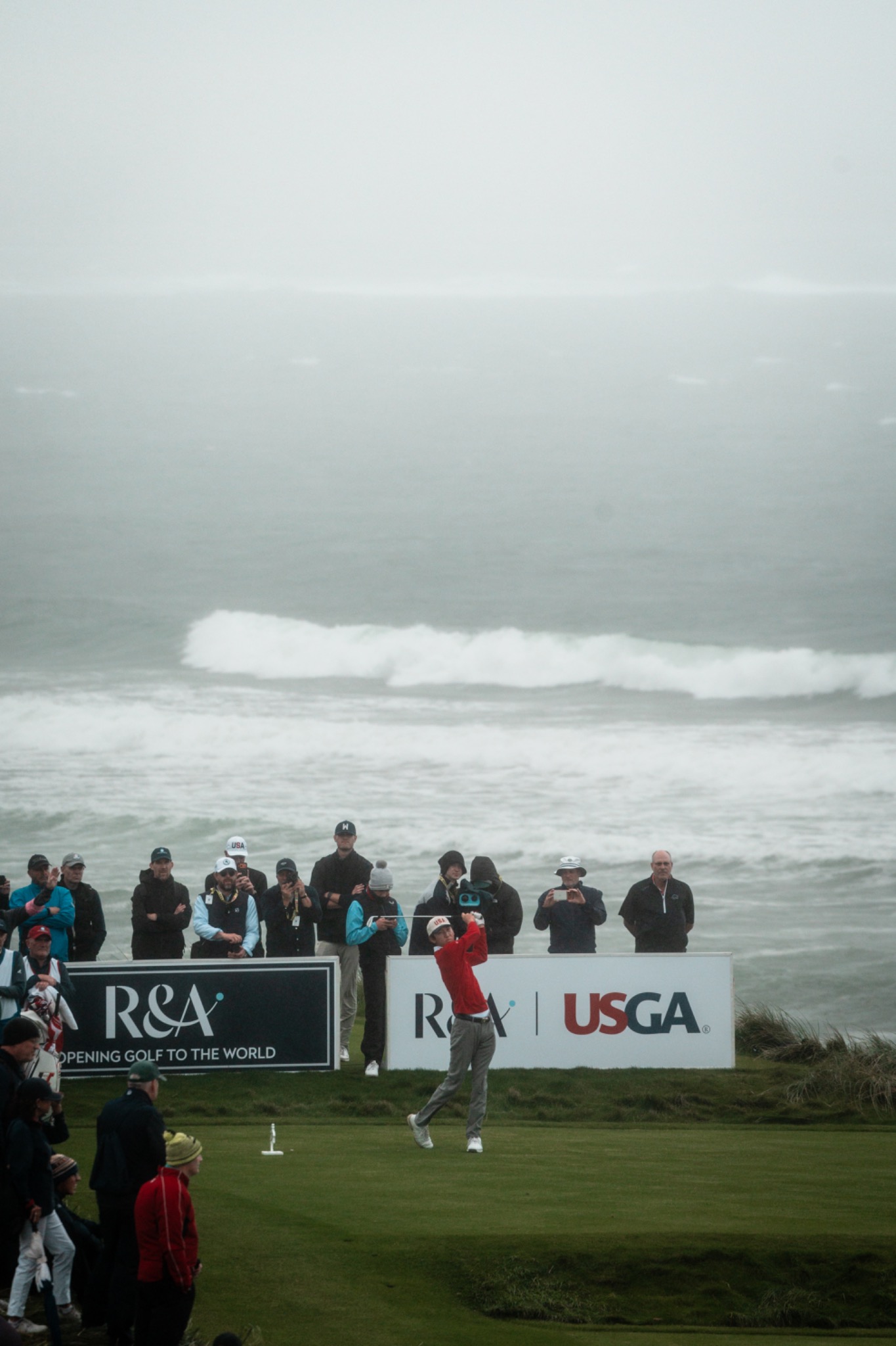 Jay Leng hitting a golf shot with the ocean behind him