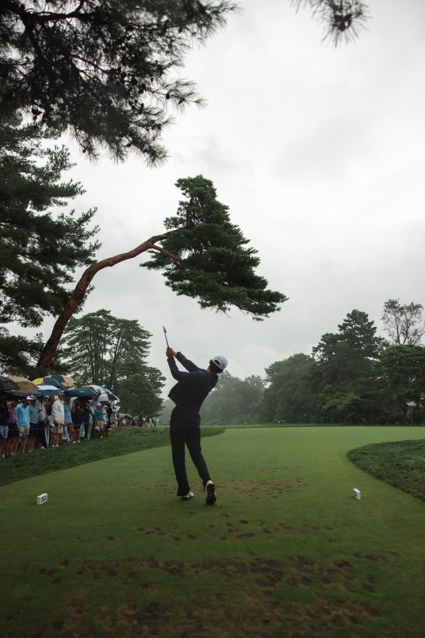 Jay Leng hitting a golf shot in rainy conditions